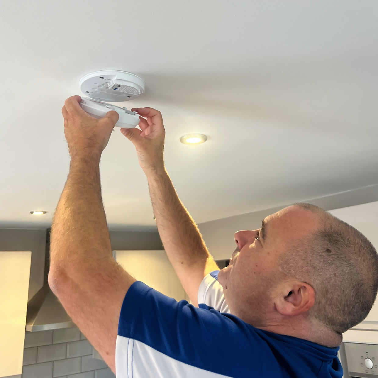 Smoke alarm installer fitting an alarm in a Camberley property